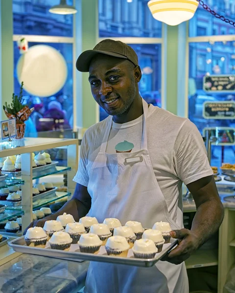 Homem preto com cupcakes na bandeja — Fotografia de Stock