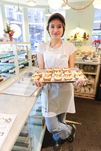 Улыбающаяся девушка с кексами у булочной — стоковое фото