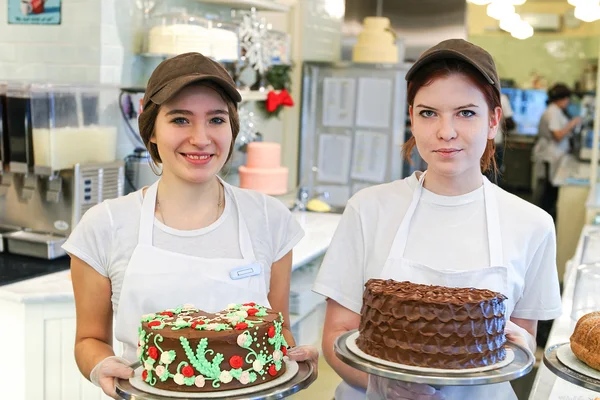 Duas meninas com bolos no balcão da padaria — Fotografia de Stock