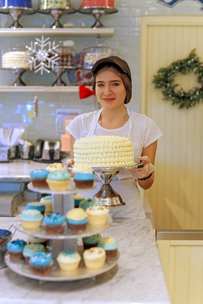 Smiling nice girl with cake at the bakery — Stock Photo, Image