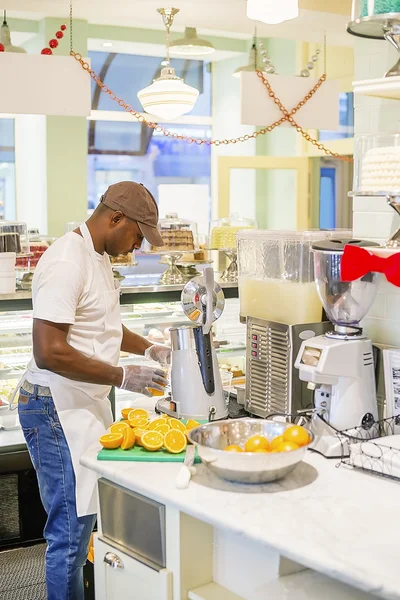 Homem negro extraindo suco de laranja no café — Fotografia de Stock