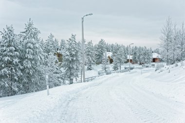 Road to cottages and trees in the snow covered Ruka in Finland clipart