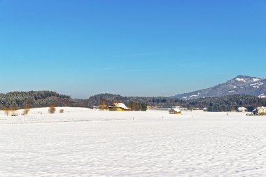 View of countryside in snow covered Switzerland in winter clipart