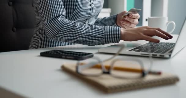 Primer plano de la mujer que ingresa datos en línea en el ordenador portátil con tarjeta de pago en la mano mientras está sentado en el lugar de trabajo en la oficina. Concepto de banca remota. — Vídeos de Stock