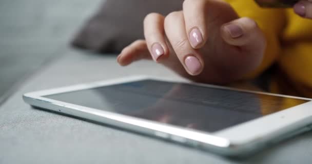 Close-up van de vrouw in de gele trui voert gegevens in over de tablet met de bankkaart in de hand. Online winkelen. — Stockvideo