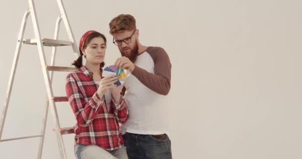 Jovem casal bonito juntos escolher a partir de paleta de cores para pintar as paredes em novo apartamento. Conceito de reparação. — Vídeo de Stock