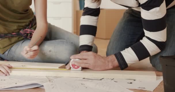男と女の密室で木の板の長さを測定し、印を付ける. — ストック動画