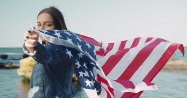 Güzel beyaz kız, arkasından Amerika 'nın bayrağını dalgalandıran deniz esintisini izliyor. Öğrenci evini özlüyor..