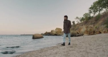 Ceketli yakışıklı, şık, yalnız bir adam ıssız bir sahilde yürüyor ve denize bakıyor. Bekar. Deniz melankolisi.