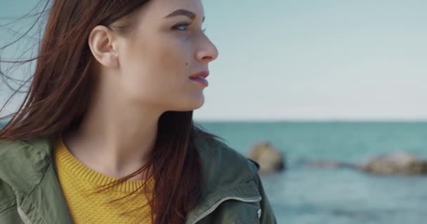 Närbild porträtt av vackra kaukasiska kvinna vänder huvudet och tittar på kameran ler på havet och blå himmel bakgrund. — Stockvideo