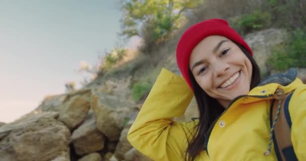 閉じるアップの若いです美しいですcaucasian女の子観光客で黄色ジャケット撮影ビデオオンカメラの背景に山の石. — ストック動画