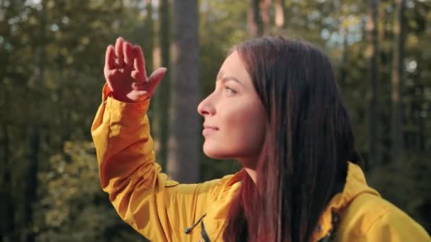 Mladá krásná kavkazská dívka turistka ve žluté bundě zkoumá ptáky na lesní mýtině dalekohledem. Výzkum a vědecká procházka. — Stock video
