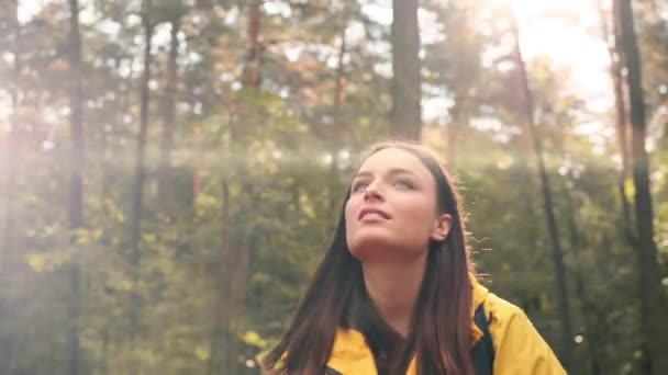 Mladá krásná dívka turista ve žluté bundě chůze v lese na slunečný den a fotí přírodu na smartphone. — Stock video