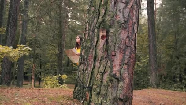 Ung vit kvinna i gul jacka går vilse i skogen med papperskarta i händerna, och ser sig desperat omkring. — Stockvideo