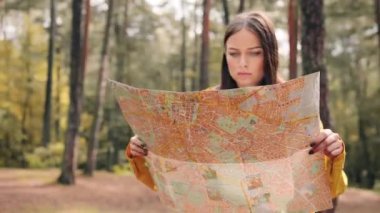 Sarı ceketli genç bir kız ormanın ortasında duruyor. Haritası açık ve etrafı karıştırıyor. Kaybolduğunu fark ediyor..