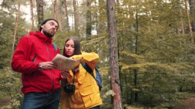 Turistlerin iki arkadaşı: erkek ve kadın, birlikte ormanda seyahat ediyorlar ve kağıt haritaya bakmanın yollarını arıyorlar..