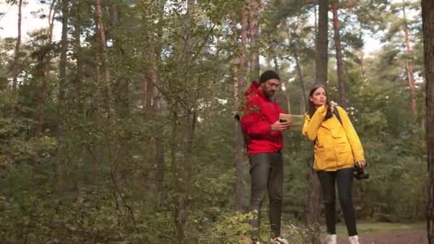 Jeune couple heureux de touristes vont en randonnée à la forêt et faire route sur carte papier. Randonnée dans la nature. — Video