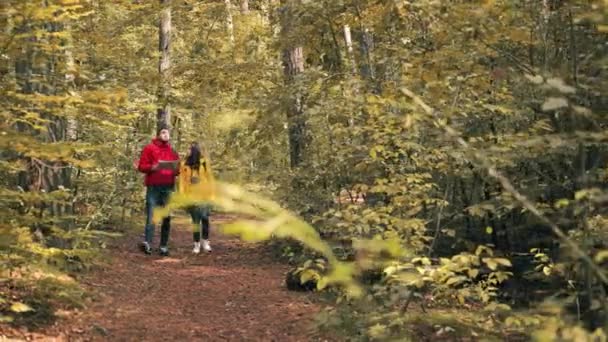 Giovane coppia cammina lungo il sentiero nella riserva forestale e si guarda intorno. Turista maschio segue le note sulla mappa. — Video Stock