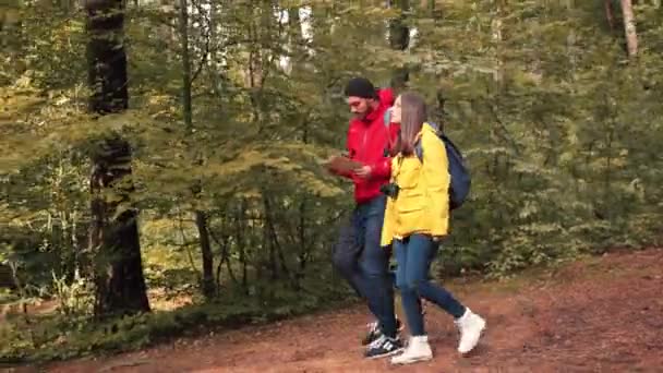 Dva přátelé turistů cestovat společně na lesní cestě a hledat správné místo při pohledu na papírové mapě. — Stock video