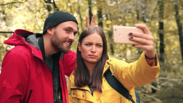 Joven pareja feliz tomando selfie mientras está de pie en el bosque. Dos adultos hacen muecas para la foto en las redes sociales. — Vídeo de stock
