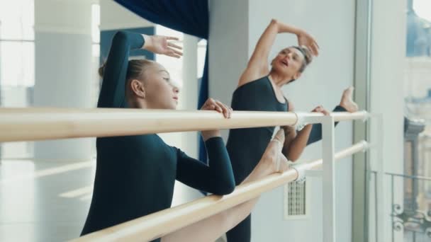 Маленька талановита дівчинка займається гімнастикою з тренером у балетній студії. Вчитель і студент виконують розтяжку перед заняттям . — стокове відео