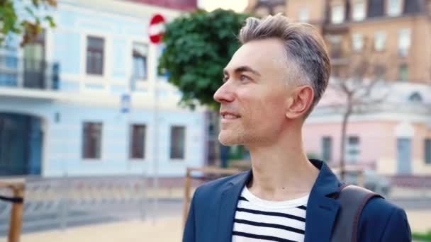 Portrait shot of middle-aged happy handsome Caucasian businessman looking and smiling at camera at city street. Outside. Close up of face of cheerful stylish man. Joyful male in summer. — Stock Video