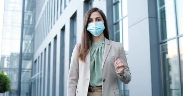 Portret van Kaukasische mooie stijlvolle vrouw met medisch masker buiten staan en tonen stop gebaar met de hand. Sociaal afstandconcept. Zakenvrouw in ademhalingsbescherming. Pandemie. — Stockvideo