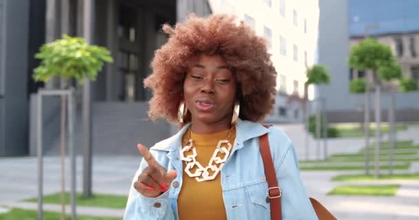 Krásná stylová mladá Afroameričanka s kudrnatými vlasy mluví do kamery, jako odmítá muže na ulici. Hezká žena propouštějící mužský obdivovatel venkovní ve městě. — Stock video