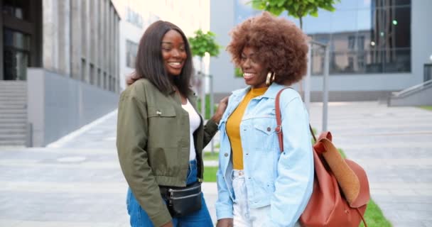 Retrato de mujeres guapas afroamericanas, mejores amigas sonriendo alegremente a la cámara y de pie en la calle de la ciudad. Elegante hermosa feliz mujeres estudiantes. — Vídeos de Stock