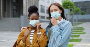 Caddede maske takıp gülümseyen melez, neşeli, genç kadınların portresi. Dışarıda çok ırklı mutlu kızlar var. Afro-Amerikan ve beyaz kadınlar. Salgın.