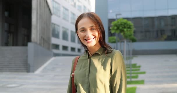Portretfoto van een blanke jonge mooie vrouw in een blauw jeans jasje met tas die op straat staat en vrolijk glimlacht naar de camera. Mooie vrolijke vrolijke vrouwelijke outdoor. — Stockvideo