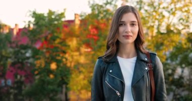 Kasabadaki parkta kameraya bakıp gülümseyen güzel beyaz, mutlu, genç bir kadının portresi. Açık havada. Güzel, neşeli bir kadın gülümsemesi Güzel, sıcak bir sonbaharda.