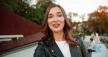 Kafkasyalı güzel bir kadının görüntüsü. Akıllı telefondan gülümsüyor ve web kamerasıyla konuşuyor. Açık havada. Güzel, mutlu, neşeli bir bayan cep telefonuyla video görüşmesiyle konuşuyor. Videochat. Video sohbeti.