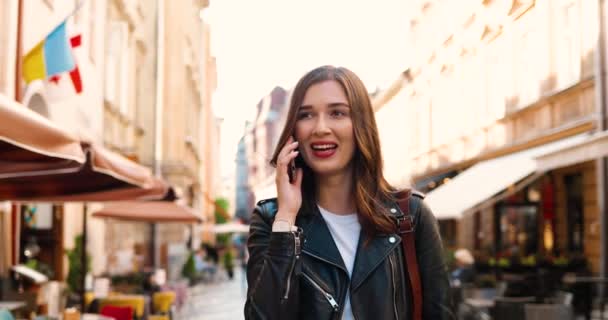 Caucasico sorrise bella donna ridendo e parlando sul cellulare mentre passeggiava per la strada in città. Abbastanza felice femmina parlando sul cellulare e passeggiando in città all'aperto. — Video Stock