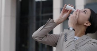 Sokakta dikilirken burun spreyi ve mendil kullanan güzel, beyaz bir kadının portresini yakından çek. Güzel, genç bir bayan üşüyormuş. Virüs konsepti. Sağlık hizmetleri. Hastalık tedavisi.