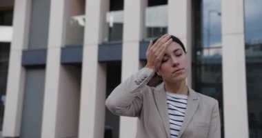 Kafkasyalı hasta genç bir kadının portresi. Baş ağrısı çekiyor ve şehirde ayakta dururken parmaklarıyla boğazına dokunuyor. Güzel hasta kadın Virüs konseptinde kendini iyi hissetmiyor.