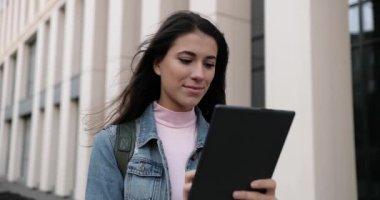 Şehirde ayakta duran ve tableti tıkırdatan mutlu genç bir kadının portresini yakından çek. Güzel, yalnız, beyaz, neşeli bir kadın dışarıda aletlere bakıyor ve gülümsüyor. Boş zaman konsepti