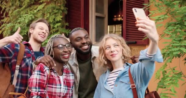 Mixed-races jonge mannen en vrouwen gelukkig vrienden staan buiten en het nemen van selfie foto met smartphone camera. Multi etnische toeristen met behulp van mobiele telefoon voor het maken van selfies foto 's. Apparaatbeeld. — Stockvideo