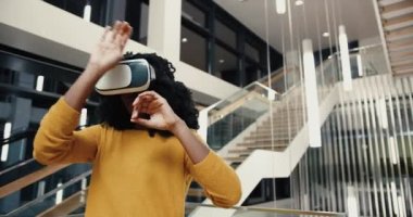 Üniversitenin lobisinde sanal gerçeklik gözlükleriyle duran genç ve güzel bir kız öğrenci bilgi aramak için jestler kullanıyor..