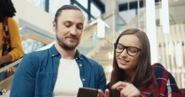 Üniversite lobisinde dikilen iki genç öğrencinin konuşmalarını kapatın. Erkek ve kız sosyal ağlardan videoları tartışıyor.