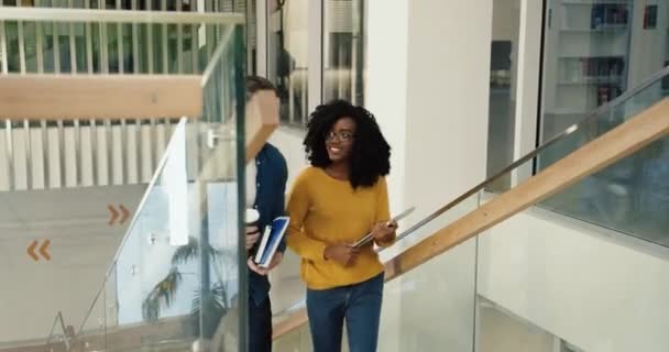 Двоє розумних молодих багатонаціональних студентів піднімаються сходами університету та обговорюють майбутні іспити, тему лекцій та академічний успіх . — стокове відео