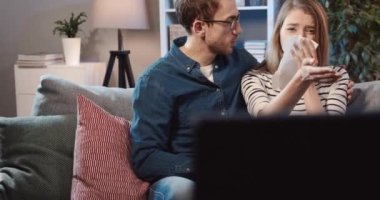 Yakışıklı adam dramatik bir filmden ağlayan ve peçeteyle gözyaşlarını silen karısını kucaklıyor ve yatıştırıyor..