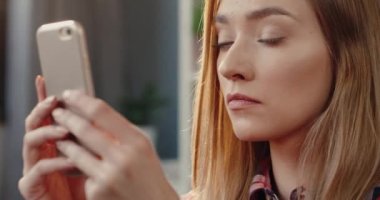 Çevrimiçi mağazada akıllı telefon kullanarak ürünlere göz atan genç ve güzel sarışın bir kadın. Tatmin olmuş kadın kullanıcı kavramı.