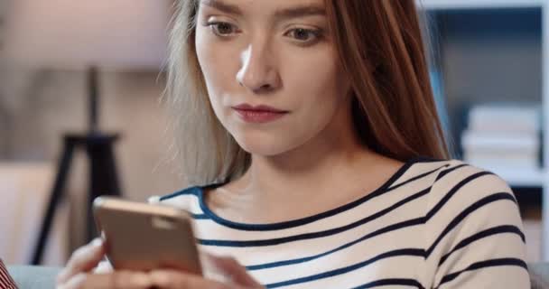 Primer plano de la joven hermosa mujer que pasa el tiempo en las redes sociales utilizando el teléfono inteligente y riendo con chistes. — Vídeo de stock