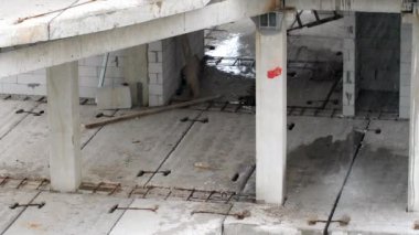 Yağmurda inşaat alanında. İnşaatçılar kötü hava koşulları nedeniyle işyerinden ayrıldılar. Beton levhalar ve önceden hazırlanmış beton yığınları suyla doludur. İşçiler zorla mola verdiler.