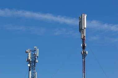 Mavi gökyüzü ve beyaz bulutun arka planında cep telefonu kulesi var. Telekomünikasyon TV kulesi. Hücresel anten. Wi-fi verici ve alıcı modülü. 
