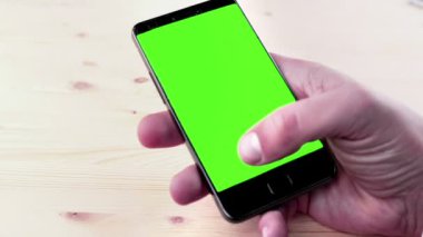 adam ellerini kullanarak bir akıllı telefon için chroma anahtar yeşil ekran üzerinde ahşap masa, smartphone ile iletişim ile mesaj yazmak