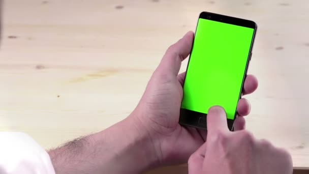 Mano del hombre usando un teléfono inteligente con croma key sobre fondo de madera, pantalla verde, estilo de vida de comunicación con el teléfono inteligente — Vídeo de stock