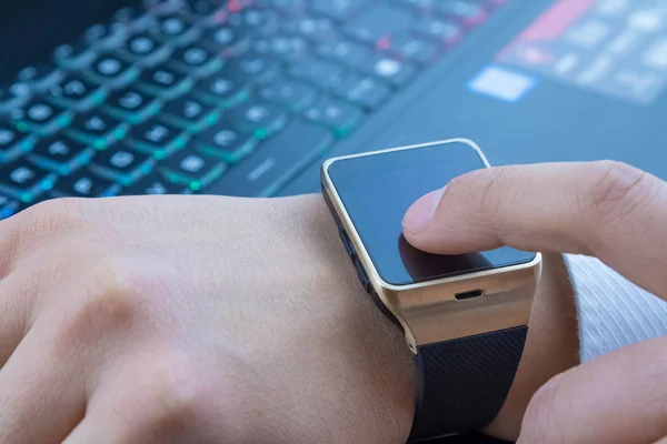 Uomo d'affari utilizzando la sua applicazione smartwatch vicino alla tastiera del computer pc sulla luce quotidiana — Foto Stock