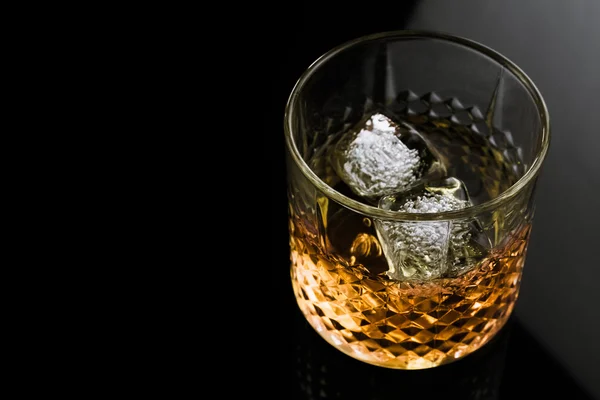Whiskey con cubitos de hielo en vidrio sobre fondo negro —  Fotos de Stock